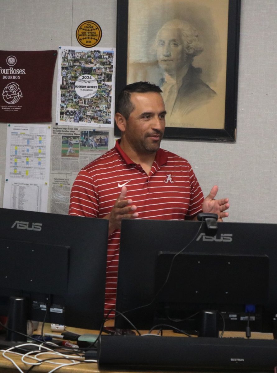 Mr. Garza standing behind his desk and giving a lecture to his students.